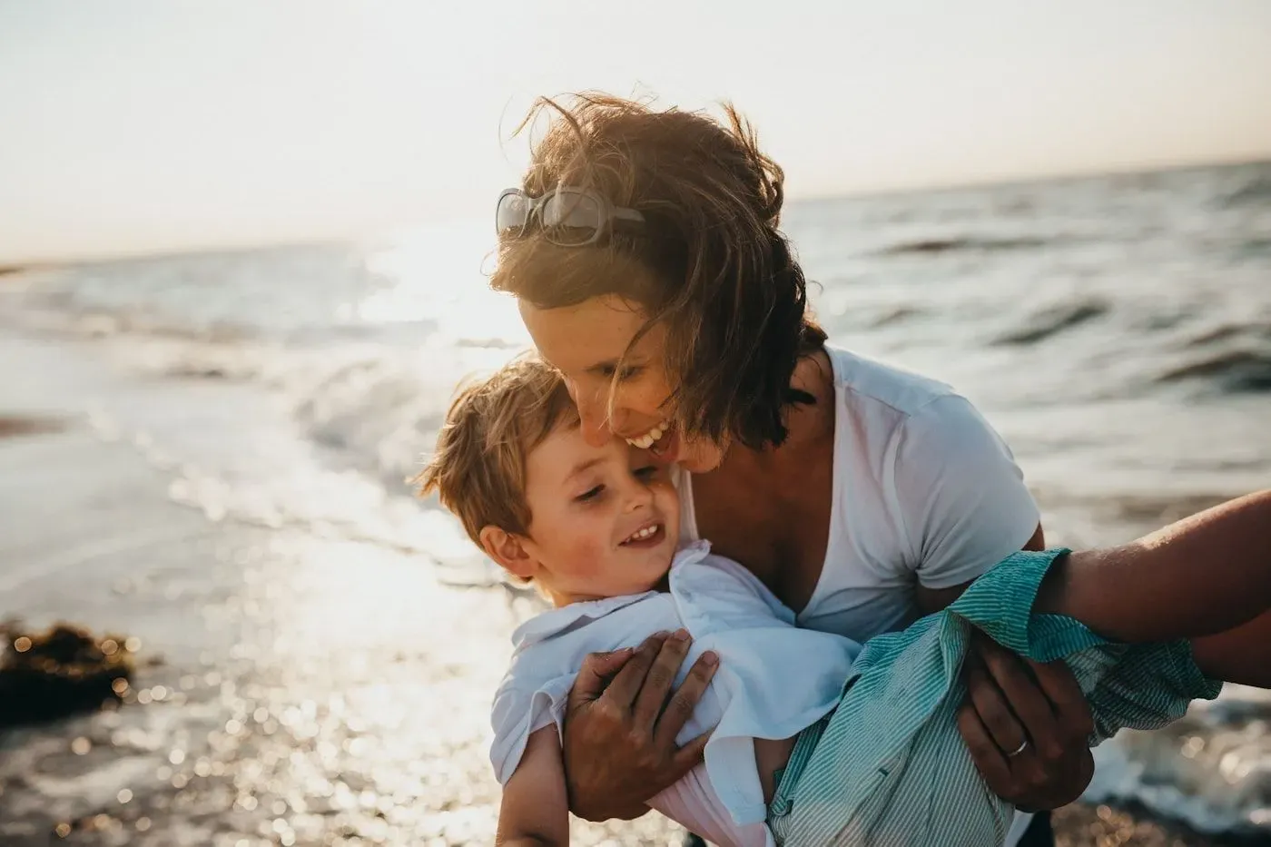 A parent holding a young child close in warm evening light.