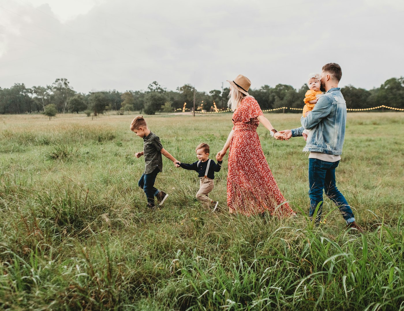 A family walking together through a sunlit golden field at the end of the day.