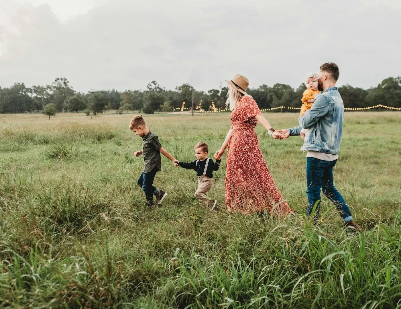 A family walking together through a sunlit golden field at the end of the day.